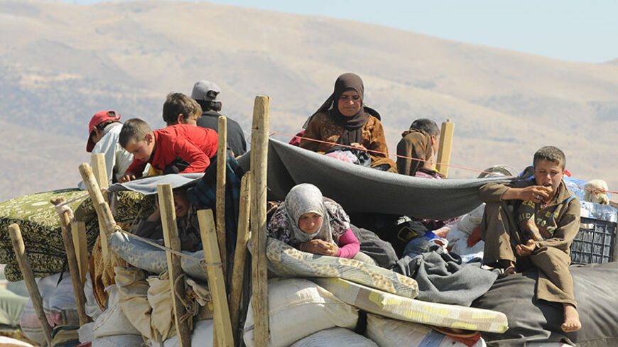 Syrian refugees, fleeing the recent fighting in Arsal, wait with their belongings in Majdel Anjar in the Bekaa valley, near the Lebanese border with Syria