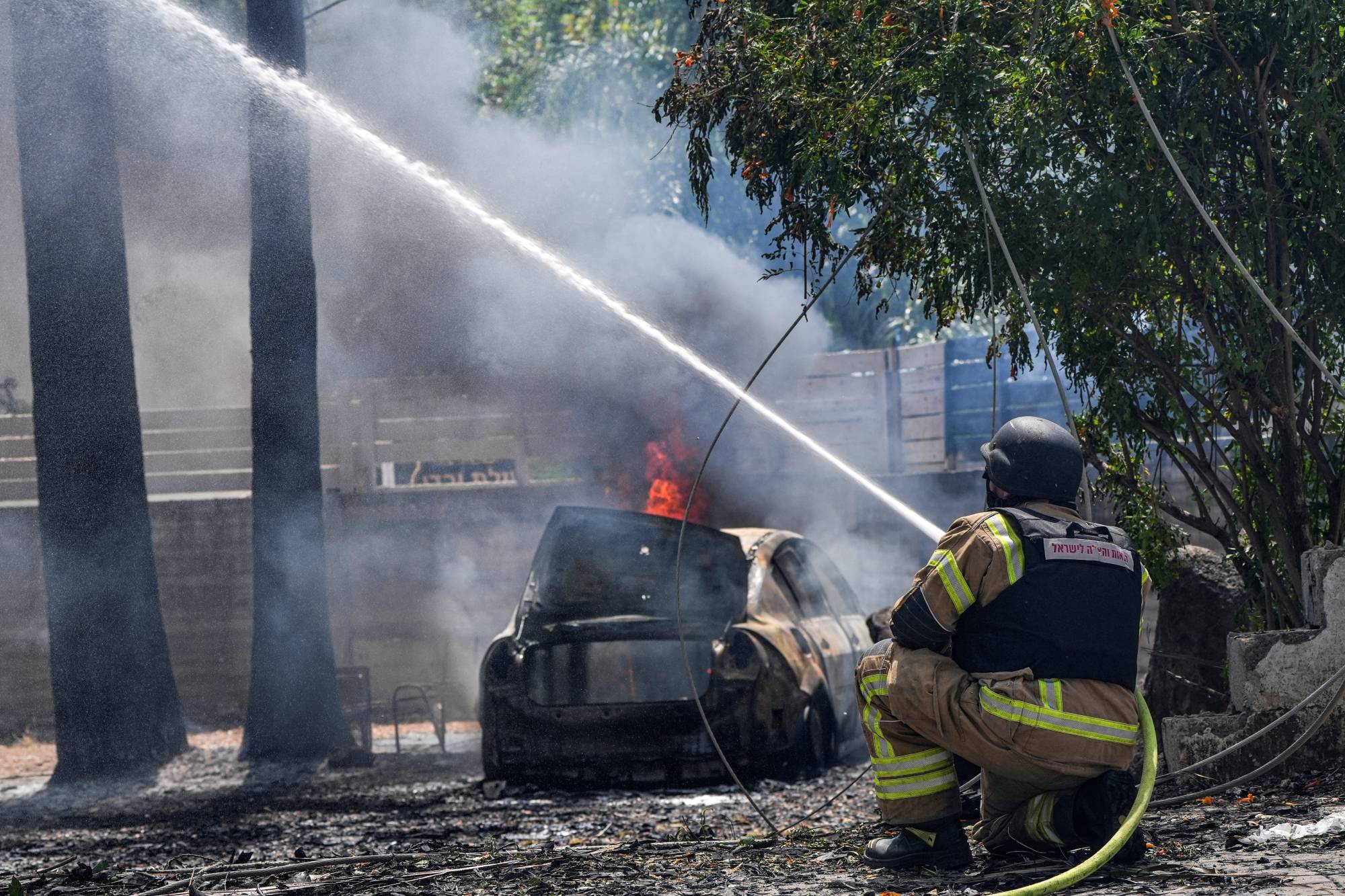 Firefighters work to put out fire at the impact site of a rocket that was fired towards Israel from Lebanon, amid ongoing cross-border hostilities between Hezbollah and Israeli forces, in Kiryat Shmona