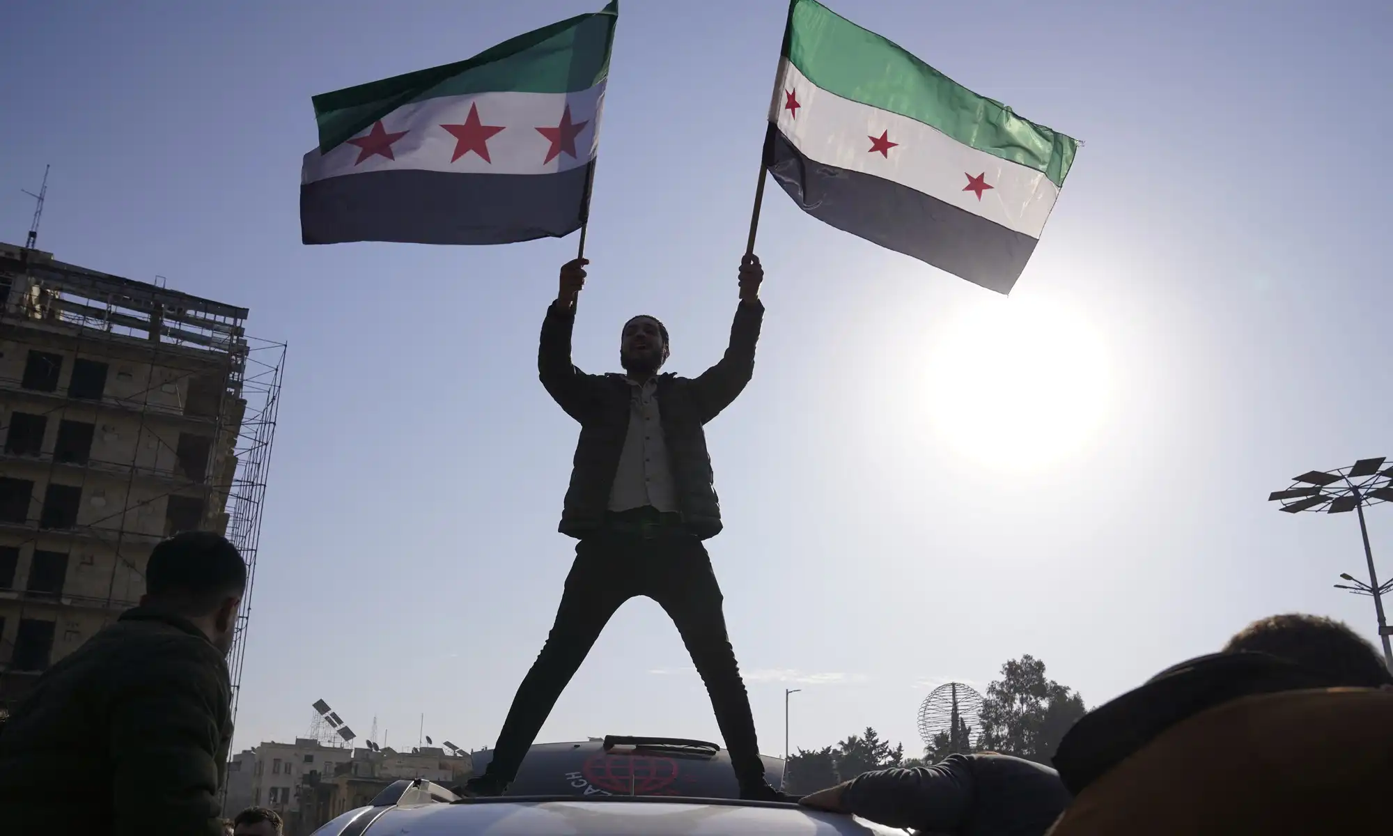 People hold the Syrian opposition flag as they celebrate, in Aleppo