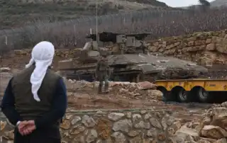 سوري يشاهد شاحنة تنقل دبابة إسرائيلية